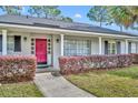 Inviting entryway with a bright red door, brick facade, and manicured landscaping, creating a welcoming entrance at 401 Sanford Ave, Longwood, FL 32750