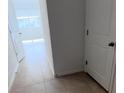 Hallway with neutral colored tiles, with white doors and trim, and an open view to a bedroom at 516 Madison Dr, Davenport, FL 33837