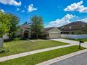 Inviting one-story home featuring a manicured lawn, lush landscaping, and an attached two-car garage at 610 Carey Way, Orlando, FL 32825