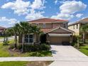 Beautiful two-story home featuring a red tile roof, attached two car garage, and well manicured lawn at 7618 Oakmoss Loop, Davenport, FL 33837