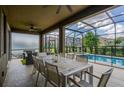 Covered patio with dining table, comfortable seating, and serene views of the pool and backyard at 7618 Oakmoss Loop, Davenport, FL 33837