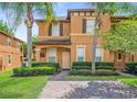 Inviting two-story townhome featuring brick-paved drive, landscaping, and covered porch at 130 Palermo St, Davenport, FL 33897