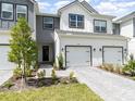 A close view displays a townhome with two-car garage, pavers, and coordinated landscaping at 1438 Brookdale Ct, Oviedo, FL 32765