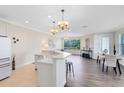 Open-concept living space featuring hardwood floors, elegant chandelier lighting, and a kitchen counter with bar stools at 1565 Corkery Ct, Winter Springs, FL 32708