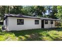 Side view of a cozy home showcasing white exteriors, black trim and lush surroundings at 2225 E Welch Rd, Apopka, FL 32712