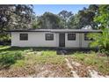 A quaint one-story home featuring black trim, white paint and a tidy, if overgrown, front yard at 2225 E Welch Rd, Apopka, FL 32712