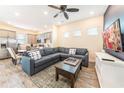 Open-concept living room and kitchen featuring a plush gray sectional sofa, wood-look tile flooring, and stainless appliances at 2978 Latitude Ln, Kissimmee, FL 34747