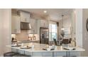 Modern kitchen featuring stainless steel appliances, gray cabinets, quartz countertops and island seating at 556 Moon Shell Cir, New Smyrna Beach, FL 32168