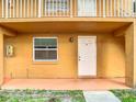 The exterior of a tan townhome featuring a single window and white door with black hardware at 734 Michigan Ct # 2, St Cloud, FL 34769
