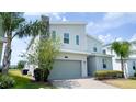 Beautiful two-story house with a stone chimney, a gray garage door, and lush greenery at 8912 Cabot Cliffs Dr, Davenport, FL 33896