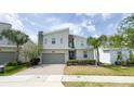 Modern two-story house with stone details, a gray garage door, and neat front lawn at 8912 Cabot Cliffs Dr, Davenport, FL 33896