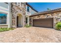 Beautiful home with a stone-accented facade, two-car garage, brick-paved driveway, and manicured landscaping at 11689 Hampstead St, Windermere, FL 34786