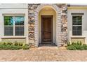 Elegant front entrance with a stone archway, dark wood door, and well-maintained landscaping at 11689 Hampstead St, Windermere, FL 34786