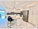 Bright kitchen with white cabinets, stainless steel appliances, island with seating, and tile flooring at 3120 Paradox Cir # 101, Kissimmee, FL 34746