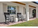 Inviting front porch featuring comfortable rocking chairs, stylish pillows and exposed beam ceiling at 5205 Saint Regis Pl, Belle Isle, FL 32812