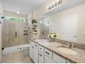 Elegant bathroom with granite countertops, dual sinks, a tiled shower, and a large mirror at 5298 Royal Point Ave, Kissimmee, FL 34746