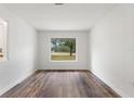 Bright living room featuring wood-look floors, modern paneling, and a large window overlooking a green space at 16336 Old Cheney Hwy, Orlando, FL 32833