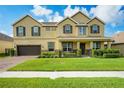 Well-maintained two-story home featuring a manicured lawn, shrubbery, and a two-car garage at 1802 Candlenut Cir, Apopka, FL 32712