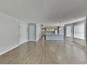 Open living space with wood-look flooring, white walls, and a view into the kitchen at 2442 Sweetwater Club Cir # 43, Kissimmee, FL 34746