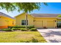 Charming yellow single-Gathering home with a two-car garage, lush landscaping, and a brick driveway on a sunny day at 3205 Sonesta Ct # F, Clermont, FL 34711