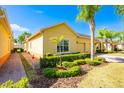 Charming yellow single-Gathering home with a two-car garage, lush landscaping, and a brick driveway on a sunny day at 3205 Sonesta Ct # F, Clermont, FL 34711