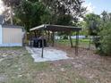 Metal carport structure with a concrete pad on a grassy lot with mature trees at 3772 Cochran St, Apopka, FL 32703