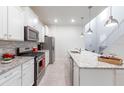 Well-equipped kitchen with stainless steel appliances, white cabinetry, granite counters, and tile backsplash at 7352 Oakmoss Loop, Davenport, FL 33837