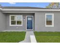 Up close view of the front door, which is blue with glass inserts. White trim borders the windows and door at 75 Guava Ter, Ocklawaha, FL 32179