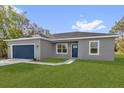 Charming single-story home with a gray exterior, blue door and garage door, and a well-manicured green lawn at 75 Guava Ter, Ocklawaha, FL 32179