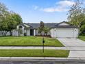 Charming single-story home with well-manicured lawn, lush trees, and a beautiful blue sky at 1012 Willa Lake Cir, Oviedo, FL 32765