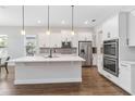 Bright, modern kitchen with white cabinets, stainless steel appliances, a center island and dark wood floors at 16753 Gullfloss Ter, Winter Garden, FL 34787