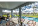 Inviting screened-in patio featuring comfortable seating, a grill, and a refreshing pool with an attached spa at 2004 Fleming Mist Pl, Kissimmee, FL 34747