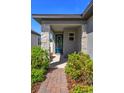 Welcoming front porch adorned with stone pillars, lush greenery, and a stylish blue front door at 2285 Mystic Maze Ln, Clermont, FL 34715