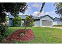 A well maintained lawn and garden compliment this charming one story home with a blue exterior at 2516 Albury Ave, Deltona, FL 32738