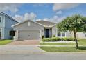 Charming single-story home with a brick driveway, manicured landscaping, and a gray stucco exterior at 299 Whirlaway Dr, Davenport, FL 33837