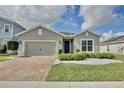 Charming single-story home with a brick driveway, manicured landscaping, and a gray stucco exterior at 299 Whirlaway Dr, Davenport, FL 33837