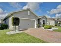 Side view of a gray house featuring a brick driveway and a two-car garage at 299 Whirlaway Dr, Davenport, FL 33837