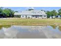Beautiful home with a metal roof, stone accents, and a serene pond reflecting the sky and the house at 3550 Kaiser Ave, St Cloud, FL 34772