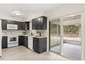 Modern kitchen featuring sleek cabinetry, white appliances, and a sliding door providing access to an outdoor patio at 4800 Beacon St, Orlando, FL 32808