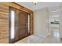 Inviting foyer featuring a rustic wood accent wall and a dark wood front door with glass panels at 5800 Spruce Creek Woods Dr, Port Orange, FL 32127