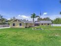 Attractive single-story yellow home on a large lot with an American flag and green lawn at 5800 Spruce Creek Woods Dr, Port Orange, FL 32127