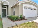 Welcoming front entrance featuring a clean walkway, lush shrubs, and a convenient two-car garage, making coming home a joy at 8118 Fan Palm Way, Kissimmee, FL 34747