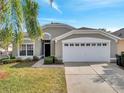 Inviting single-story home with a lush green lawn, swaying palm tree, and a convenient two-car garage adding practicality at 8118 Fan Palm Way, Kissimmee, FL 34747