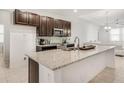 Modern kitchen featuring dark wood cabinets, stainless steel appliances, granite countertops, and an open layout at 9188 Chandler Dr, Groveland, FL 34736