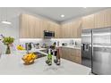 Modern kitchen with stainless steel appliances, sleek countertops, and light wood cabinets at 17407 Hidden Forest Dr, Clermont, FL 34714