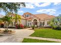 Beautiful home exterior features a tile roof, manicured landscaping, and a circular driveway at 10664 Emerald Chase Dr, Orlando, FL 32836