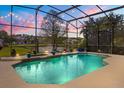 Screened pool area with a waterfall feature, string lights, and a view of a lake at 10664 Emerald Chase Dr, Orlando, FL 32836