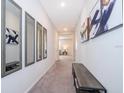 Hallway with neutral colored carpet and paint, decorated with contemporary art and mirrors at 1092 Sugarwood St, Davenport, FL 33837