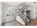 Bright foyer with wood-look floors, decorative rug, stairway with white railing and decorative cabinet at 12067 Eastmoor Dr, Winter Garden, FL 34787