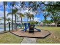 Community playground area with blue slide, palm trees, and lush greenery, perfect for Gathering fun at 13416 Greenpointe Dr, Orlando, FL 32824